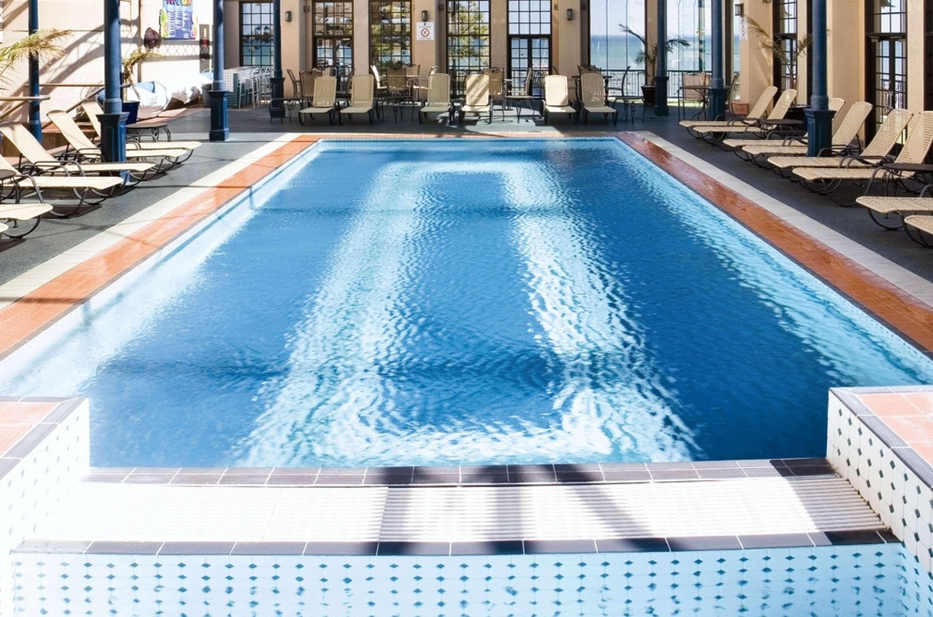 Stamford Grand Adelaide Hotel เกลเนลก์ ภายนอก รูปภาพ The photo shows an indoor swimming pool with a pristine blue surface. The pool is surrounded by a tiled deck and has lounge chairs lined up along the sides. Large windows allow natural light to flood the area, creating a bright and inviting atmospher