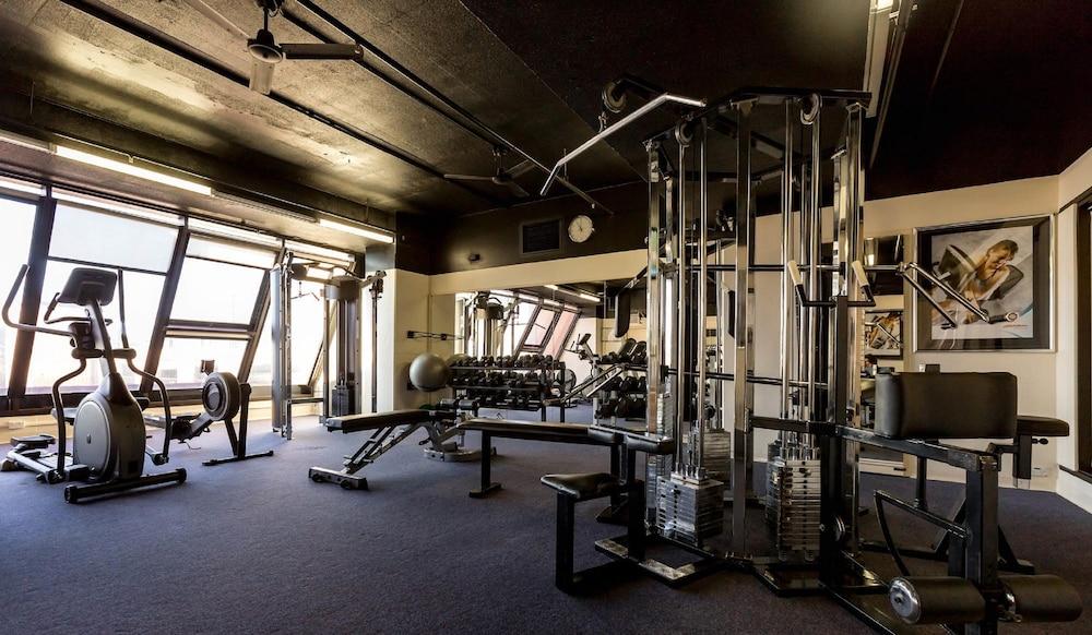 Stamford Grand Adelaide Hotel เกลเนลก์ ภายนอก รูปภาพ The photo shows the interior of a gym or fitness room. It includes various exercise equipment, such as a multi-station weight machine and rowing machine. The space is well-lit with large windows allowing natural light in, and the walls are decorated 