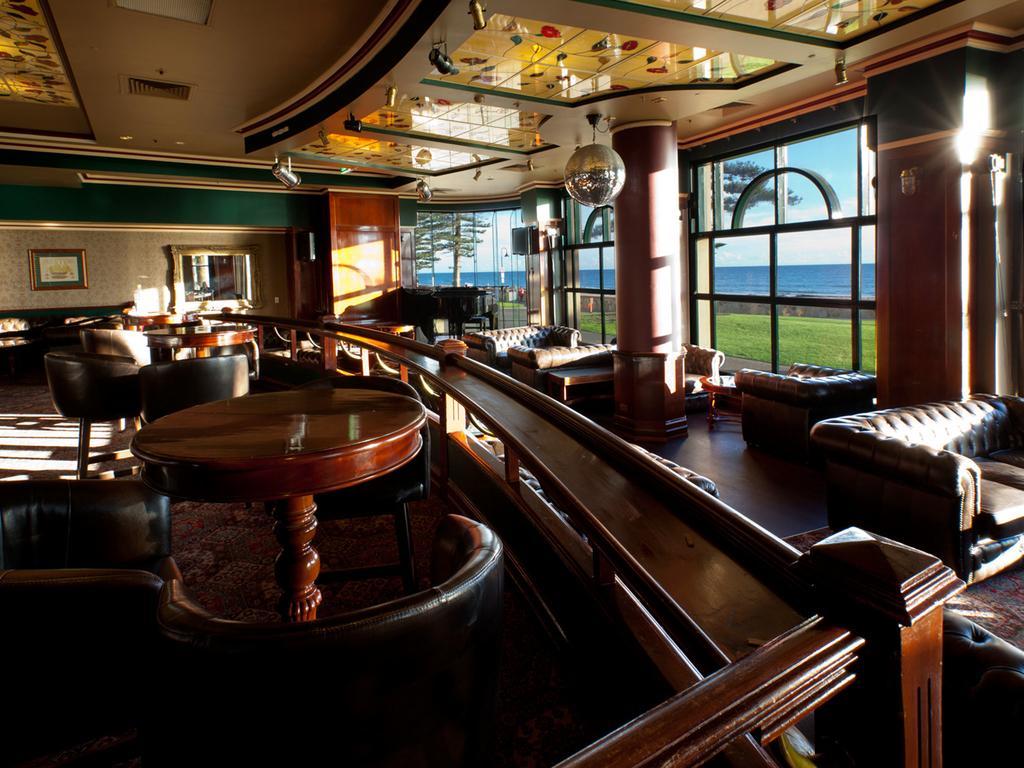 Stamford Grand Adelaide Hotel เกลเนลก์ ภายนอก รูปภาพ The photo depicts a stylish and inviting interior of a lounge or bar. It features comfortable leather seating, wooden tables, and large windows that provide a view of the outdoors. The ceiling is adorned with decorative elements, and there’s a disco 