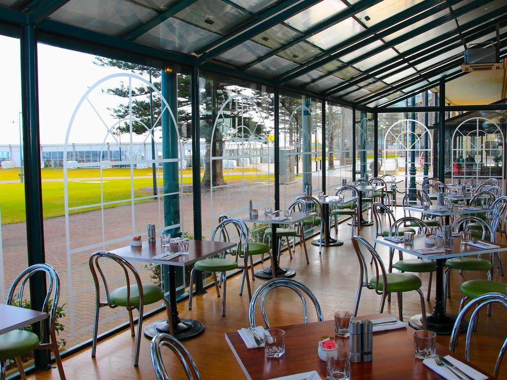 Stamford Grand Adelaide Hotel เกลเนลก์ ภายนอก รูปภาพ The photo shows the interior of a restaurant with a modern design. The space features several tables with green chairs, arranged in a way that allows for ample seating. Large glass windows provide a view of the outside, creating a bright and open atm