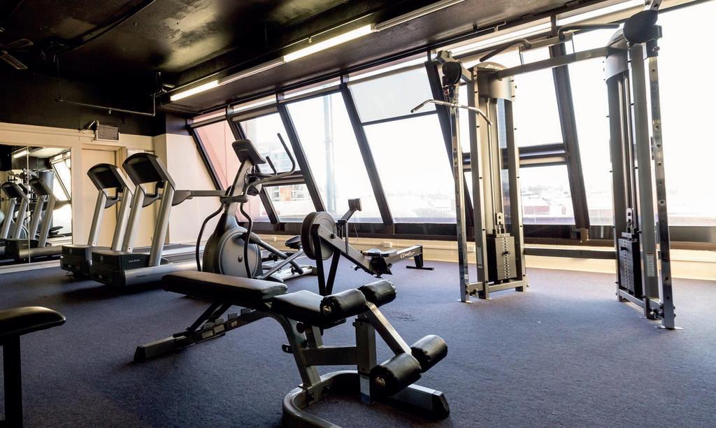 Stamford Grand Adelaide Hotel เกลเนลก์ ภายนอก รูปภาพ The photo shows a modern gym interior with several exercise machines. There are cardio machines, likely including treadmills and possibly an elliptical machine, along one side. In the center, there is a weight bench and a rowing machine. Additionally